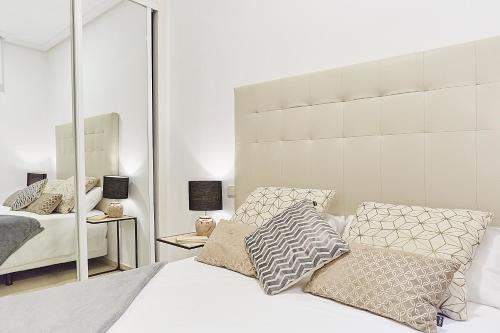 1 dormitorio con cama blanca y espejo grande en LEEWAYS APARTMENT XX in GRAN VÍA en Madrid