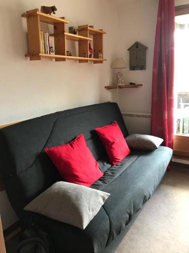 un sofá negro con almohadas rojas en la sala de estar. en STUDIO MONTAGNE 4 PERSONNES LE SEIGNUS BAS en Allos