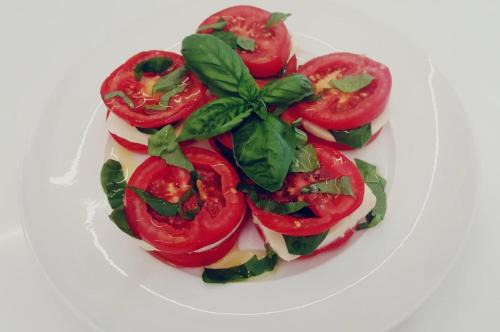 a plate of food with tomatoes and basil on it at Giardini Mon Plaisir in Trapani