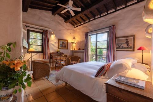 a bedroom with a bed and a desk and windows at Château De Riell in Molitg les Bains