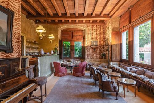 a living room with a piano and tables and chairs at Château De Riell in Molitg les Bains