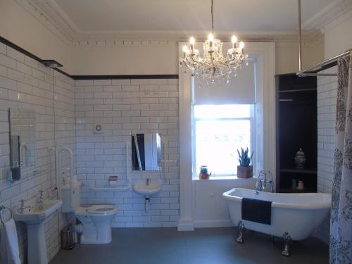 a bathroom with a chandelier and a tub and a sink at The Warren Belfast in Belfast