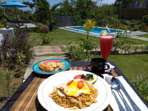 a table with a plate of food and a drink at The Pande Hill Homestay in Uluwatu