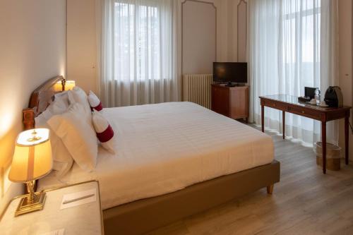 a bedroom with a bed and a desk and a television at Palace Grand Hotel Varese in Varese