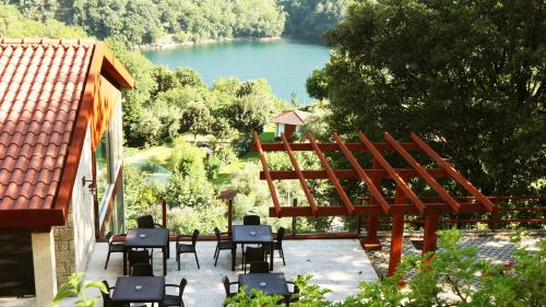 a patio with tables and chairs and a view of a lake at Agrinho Suites & Spa Gerês in Valdosende