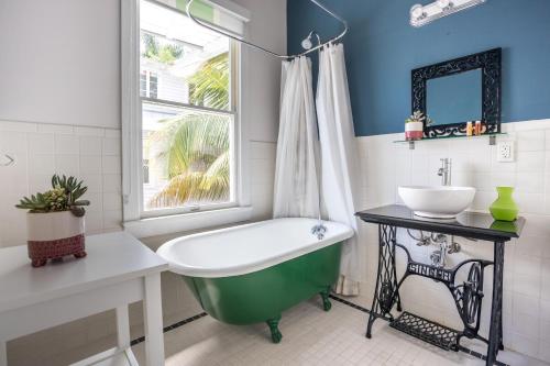 a bathroom with a green tub and a sink at Selina Miami River in Miami