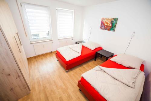 a bedroom with two beds and a red couch at Fewo Goldene Krone Leipzig mit Tiefgarage in Leipzig