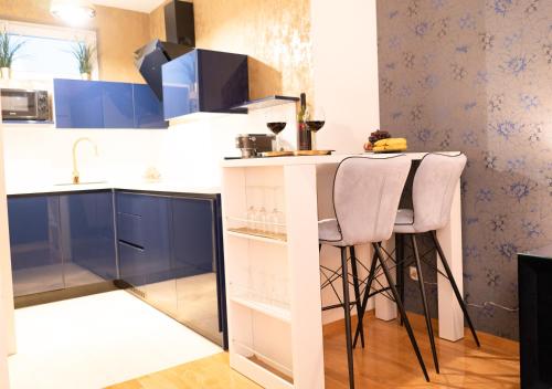 a kitchen with blue cabinets and a counter with stools at Jacuzzi studio apartman Mare's in Zagreb