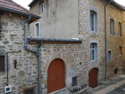 - un vieux bâtiment en pierre avec une porte rouge dans l'établissement Maison Gîte Nanie, à Arbois