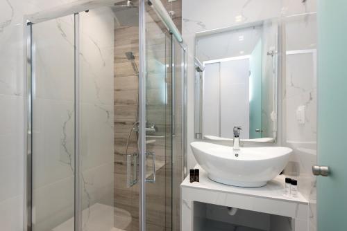 a bathroom with a sink and a glass shower at Melina Bay Boutique Hotel in Kassiopi