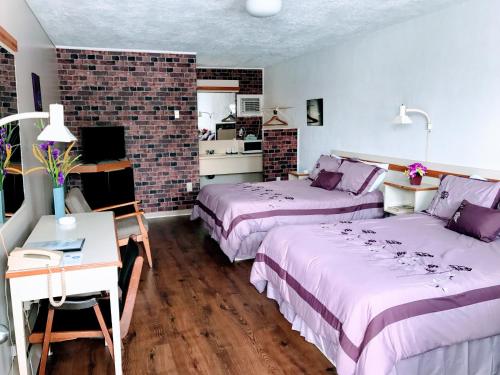 a bedroom with two beds and a table and a desk at Motel Belle Riviere in Saint-Jean-sur-Richelieu