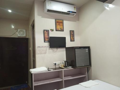 baño con lavabo y TV en la pared en Kanha Paying Guest House, en Varanasi
