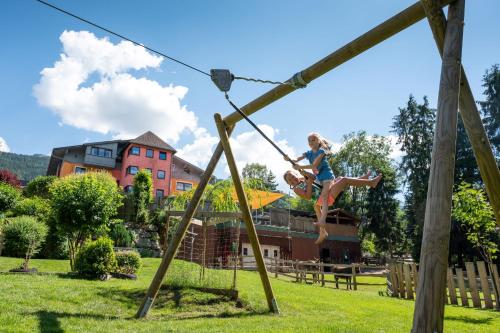 a little girl jumping on a rope swing in a park at Bliem's Familienhotel in Haus im Ennstal
