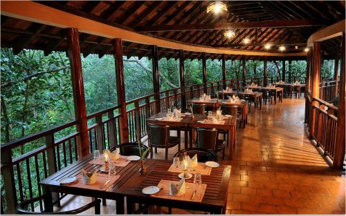 un restaurant avec des tables et des chaises en bois sur un balcon dans l'établissement Vythiri Resort, à Vythiri
