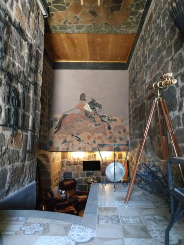 a tripod and a painting on a wall with a fireplace at Hye Aspet Հայ Ասպետ in Gyumri