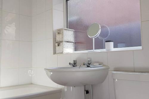uma casa de banho branca com um lavatório e uma janela em Chester City Centre House, Recently Furnished em Chester