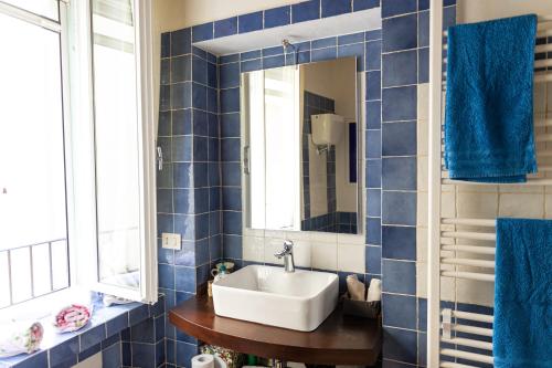 a blue tiled bathroom with a sink and a mirror at Casa vacanze al Castello. in Mugnano