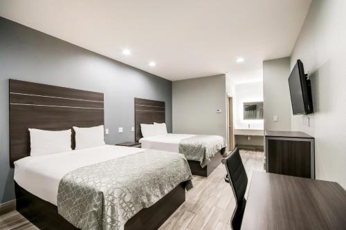 ヒューストンにあるAmericas Best Value Inn & Suites NE Houston Downtown I-610のベッド2台と薄型テレビ付きのホテルの部屋