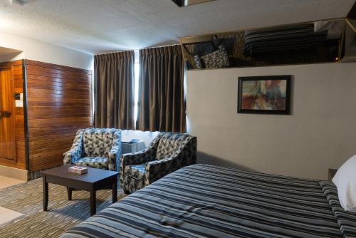 Habitación de hotel con cama y silla en Deluxe Inn en Toronto