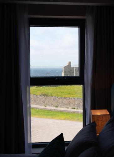a window with a view of the ocean and a castle at Rooms at The Marine in Ballybunion