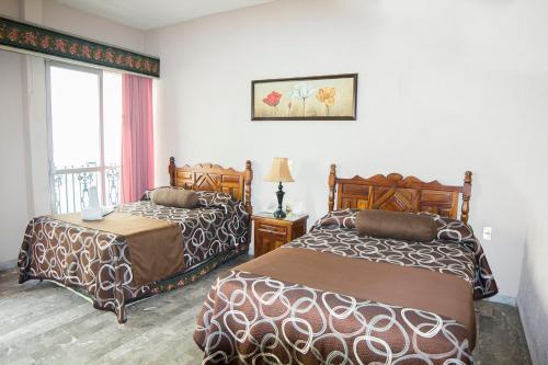 a hotel room with two beds and a window at Hotel San Jorge in Tepic