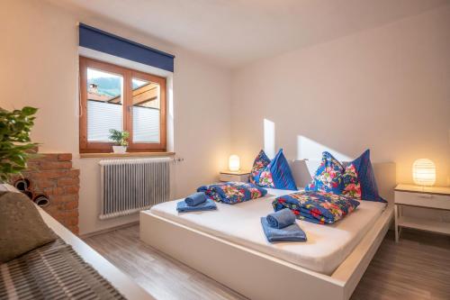 sypialnia z łóżkiem z niebieskimi poduszkami i oknem w obiekcie Salven-Lodge w mieście Hopfgarten im Brixental