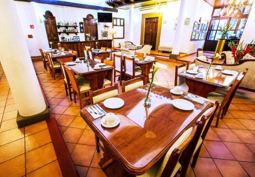 a restaurant with wooden tables and chairs in a room at Grand Guadalupe by Inmense in San Cristóbal de Las Casas