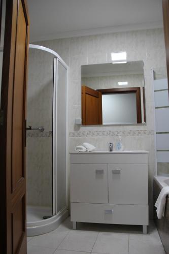 a bathroom with a sink and a shower and a mirror at Doca do Cavacas Apartment in Funchal