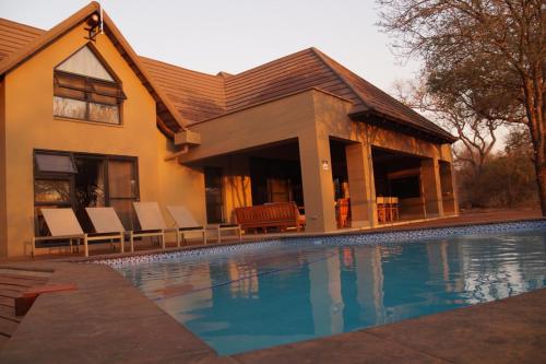 uma casa com piscina em frente a uma casa em Uchawi wa Afrika em Marloth Park