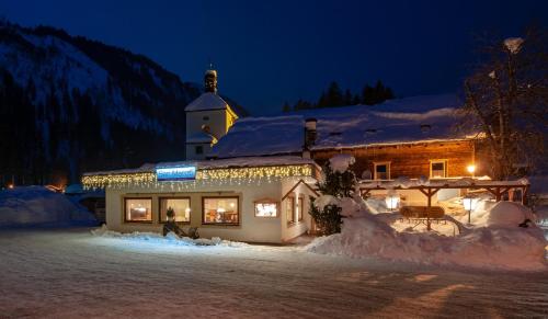 a building with christmas lights in the snow at night at Gasthaus Traube in Bichlbach