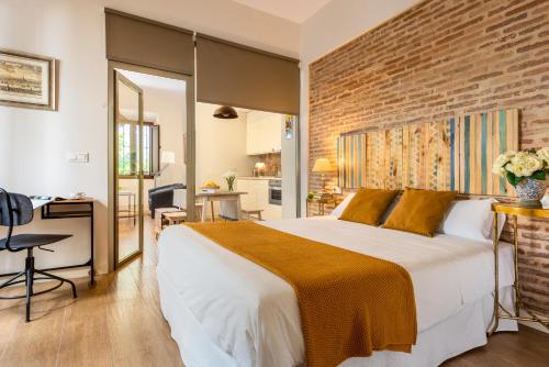 - une chambre avec un grand lit et un mur en briques dans l'établissement Misterhost Triana Patio de las Flores, à Séville