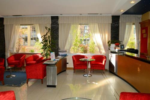 a bar in a restaurant with red chairs and windows at Hotel Giotto in Turin