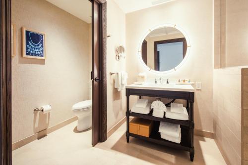 
a bathroom with a toilet, sink and mirror at Harbor View Inn in Santa Barbara
