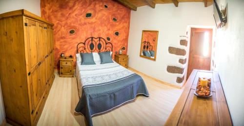 1 dormitorio con 1 cama y pared de piedra en La Casa Verde, en Las Casas