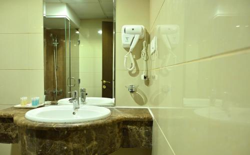 baño con lavabo y teléfono en la pared en Hayah Plaza Hotel en Medina