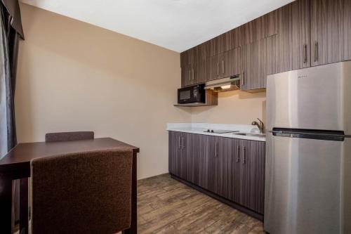 a kitchen with wooden cabinets and a stainless steel refrigerator at Baymont by Wyndham Tri-Cities/Kennewick WA in Kennewick