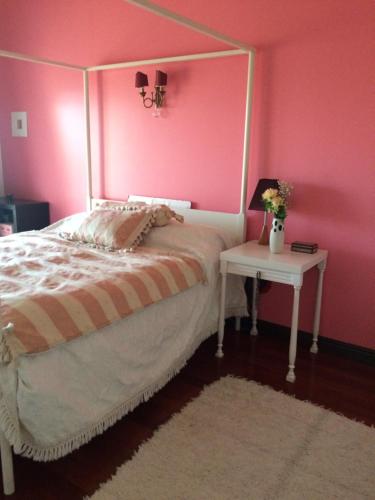 Dormitorio rosa con cama y mesa auxiliar en Sunny Suites Golf and Free Parking Guest House, en Lisboa