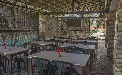 a restaurant with tables and chairs and a brick wall at Pousada Por do Sol in Barra Nova