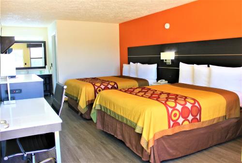 2 camas en una habitación de hotel con paredes de color naranja en Travel Inn Eutaw, en Eutaw