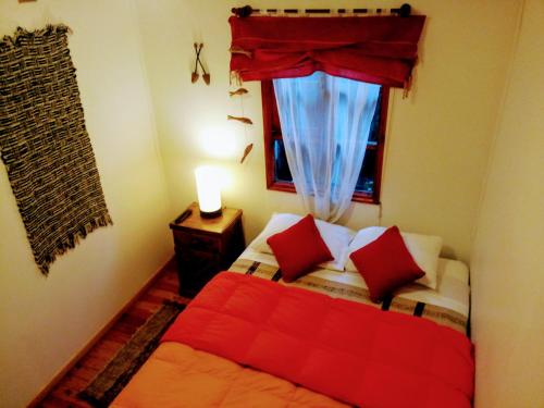 a bedroom with a bed with red pillows and a window at Hostal Torre de Babel in Castro