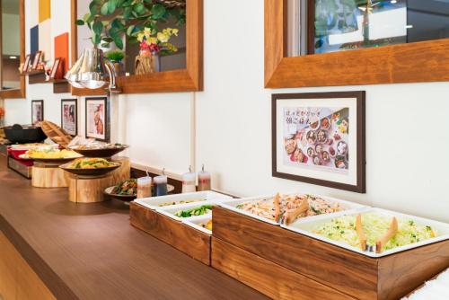 a buffet with several trays of food on a counter at Vessel Hotel Kanda Kitakyushu Airport in Kanda