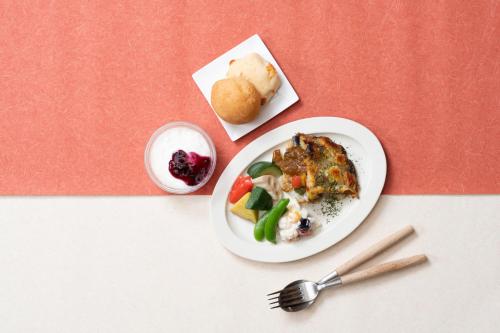 a plate of food with vegetables and a plate of bread at Vessel Hotel Kanda Kitakyushu Airport in Kanda