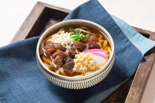 a bowl of soup with meat and rice on a wooden tray at Vessel Hotel Kanda Kitakyushu Airport in Kanda