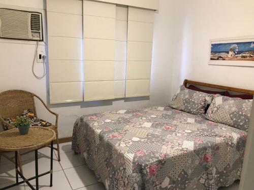 a bedroom with a bed and a table and a chair at Lindo Apartamento em Arraial in Arraial do Cabo