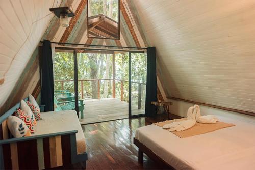 a attic bedroom with two beds and a large window at Calala Lodge in Cabuya