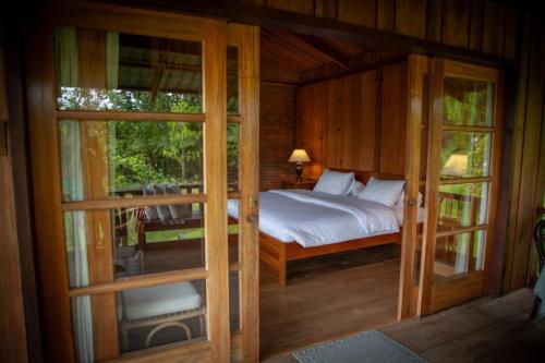 a bedroom with a bed and some glass doors at Gardenia Country Inn in Tomohon