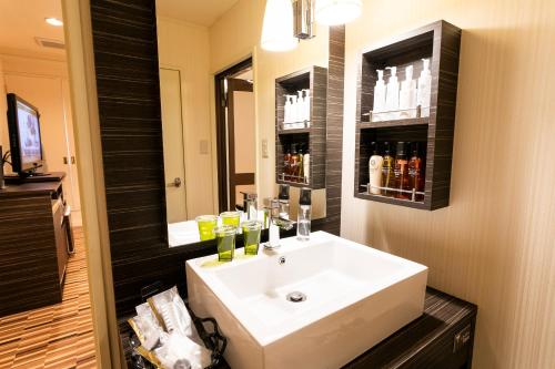 La salle de bains est pourvue d'un lavabo blanc et d'un miroir. dans l'établissement Hotel WILL Kashiwa (Adult Only), à Kashiwa