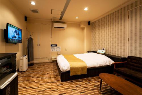 um quarto com uma cama e uma televisão de ecrã plano em Hotel WILL Kashiwa (Adult Only) em Kashiwa