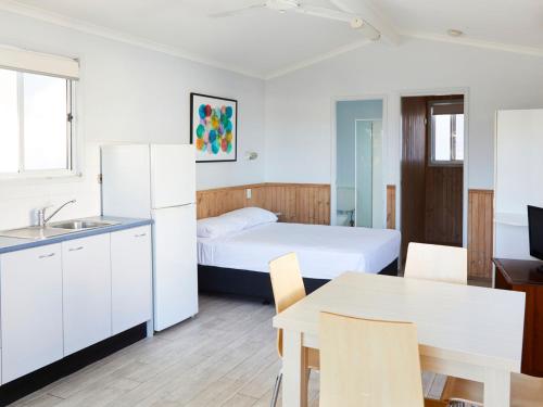 a room with a bed and a kitchen and a table at Crescent Head Holiday Park in Crescent Head