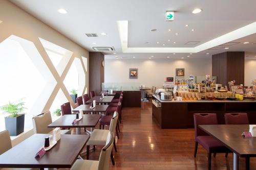 a restaurant with tables and chairs and a counter at Hotel Hokke Club Niigata Nagaoka in Nagaoka